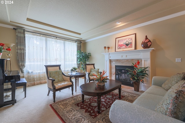 living area with a tray ceiling, a premium fireplace, ornamental molding, carpet flooring, and a textured ceiling