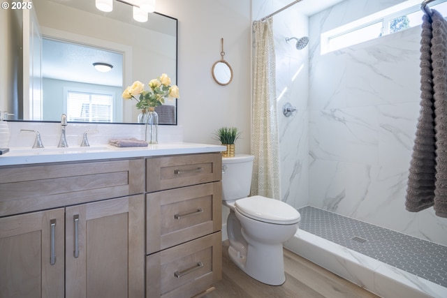 full bathroom featuring wood finished floors, a stall shower, vanity, and toilet