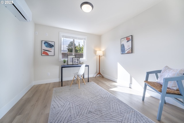 office with an AC wall unit, light wood finished floors, and baseboards