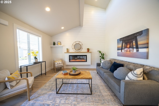 living area with high vaulted ceiling, a glass covered fireplace, recessed lighting, and wood finished floors