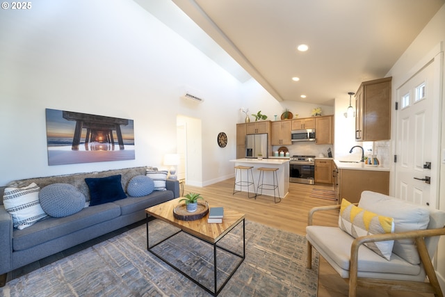 living area featuring light wood finished floors, recessed lighting, visible vents, high vaulted ceiling, and baseboards