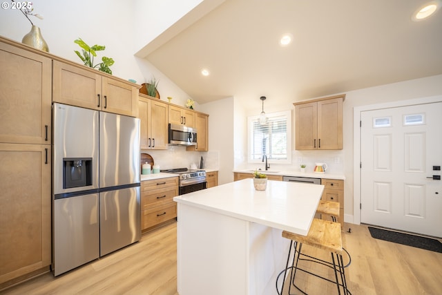 kitchen with a breakfast bar, stainless steel appliances, light countertops, light brown cabinets, and pendant lighting