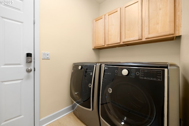 laundry room featuring washing machine and dryer, cabinet space, and baseboards