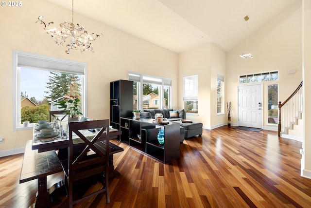 living room with a notable chandelier, high vaulted ceiling, stairway, wood-type flooring, and baseboards