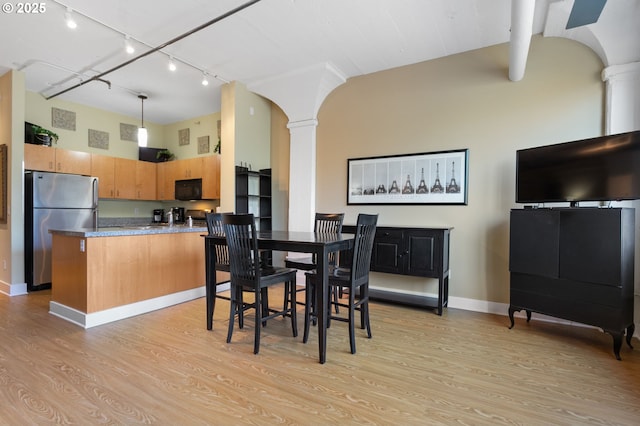 dining space with arched walkways, decorative columns, track lighting, and light wood-type flooring