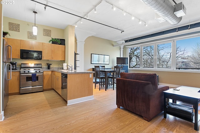 kitchen featuring track lighting, a peninsula, ornate columns, light wood finished floors, and appliances with stainless steel finishes