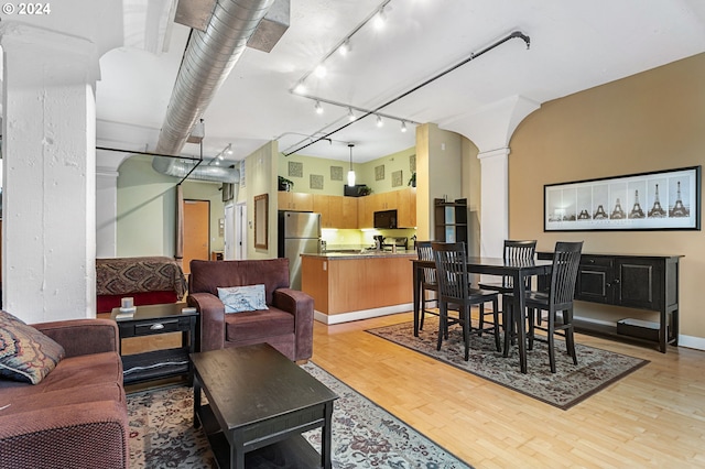 interior space featuring ornate columns, rail lighting, and light wood finished floors
