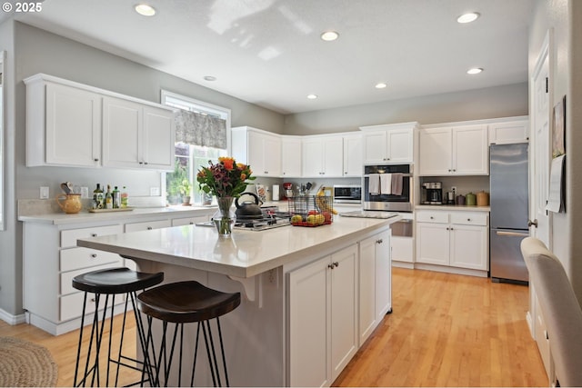 kitchen with stainless steel appliances, light wood-style flooring, white cabinetry, and recessed lighting