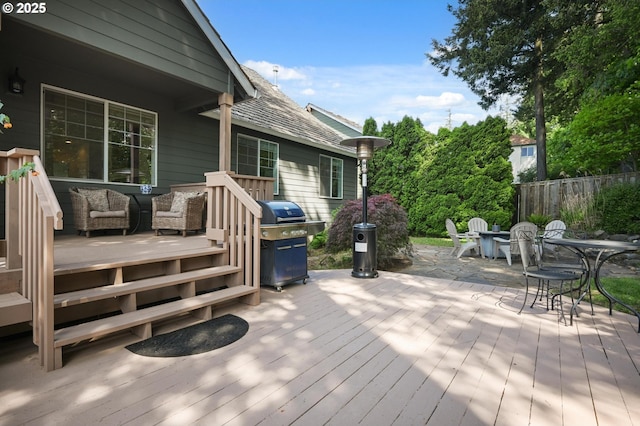 wooden deck with grilling area, outdoor dining space, and fence