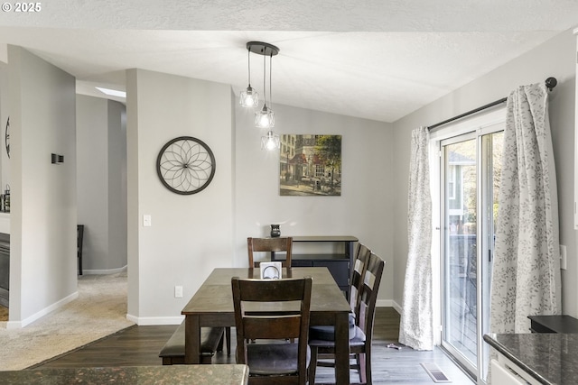 dining area with lofted ceiling, dark hardwood / wood-style flooring, and a textured ceiling