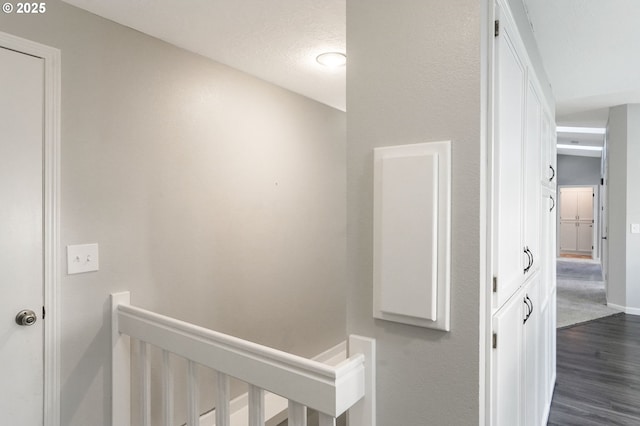 hall featuring dark wood-type flooring and a textured ceiling