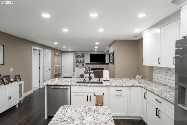 kitchen with stainless steel appliances, white cabinetry, sink, and light stone counters