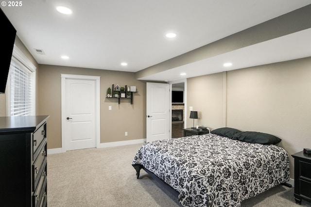 bedroom with light carpet and a fireplace