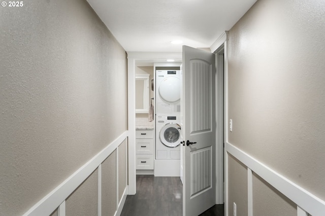 laundry area featuring stacked washer / dryer and dark hardwood / wood-style flooring