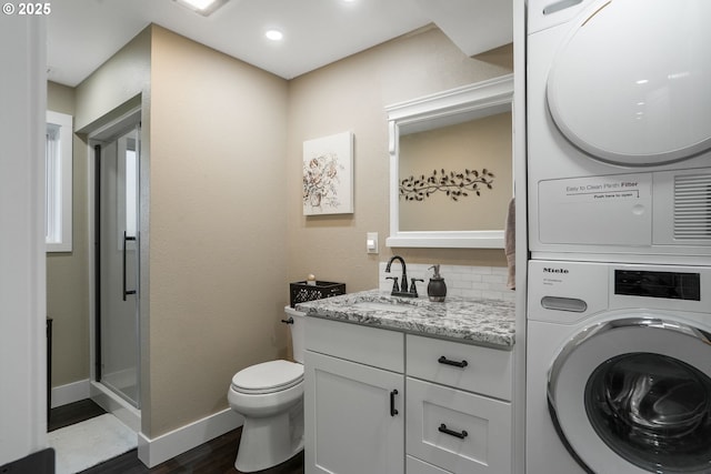 bathroom featuring stacked washer and dryer, hardwood / wood-style flooring, backsplash, vanity, and toilet