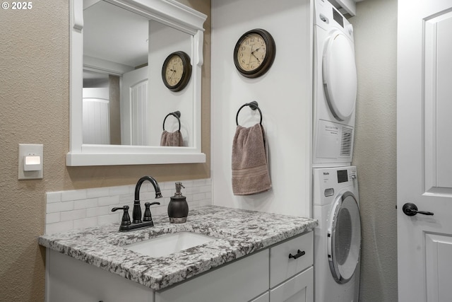 bathroom with vanity, stacked washer / drying machine, and decorative backsplash