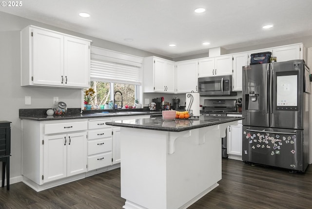 kitchen with sink, appliances with stainless steel finishes, a center island, white cabinets, and dark hardwood / wood-style flooring