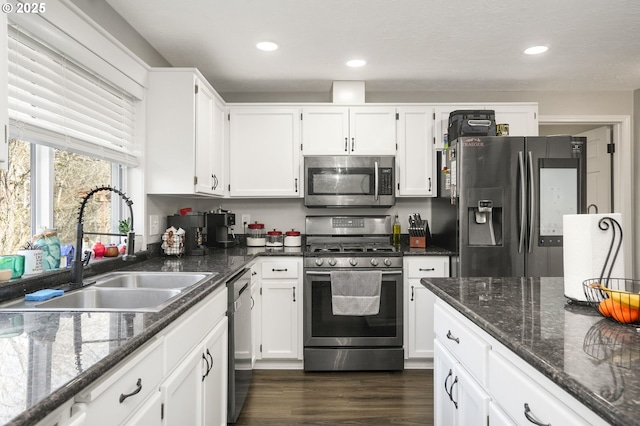 kitchen featuring stainless steel appliances, white cabinetry, sink, and dark stone counters