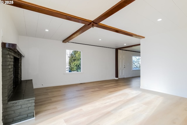 unfurnished living room with beamed ceiling, a fireplace, and light hardwood / wood-style floors