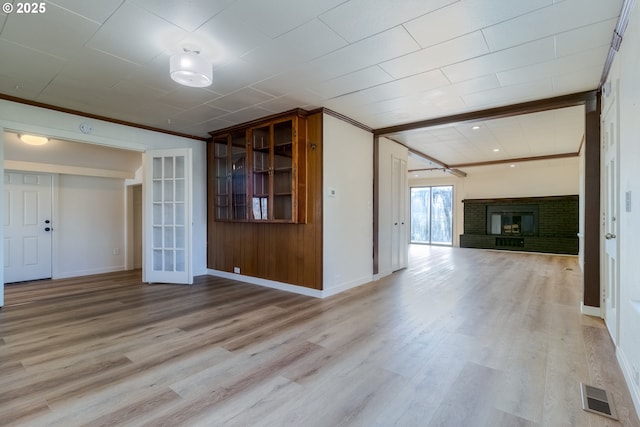 interior space with ornamental molding, a brick fireplace, and light hardwood / wood-style floors