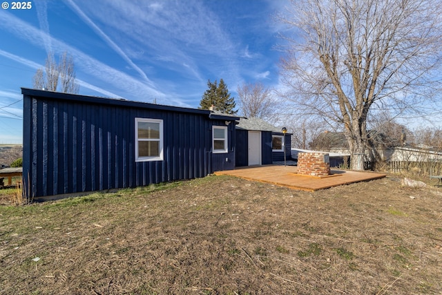 back of property with a wooden deck and a lawn