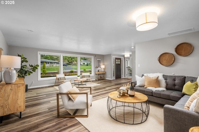 living area featuring wood finished floors, visible vents, and baseboards