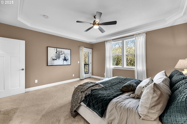 bedroom with a raised ceiling, light colored carpet, ceiling fan, and baseboards