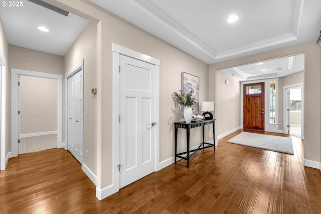 foyer with hardwood / wood-style flooring, baseboards, and a raised ceiling