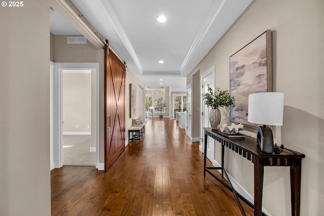 hall featuring a barn door, recessed lighting, dark wood-type flooring, baseboards, and crown molding