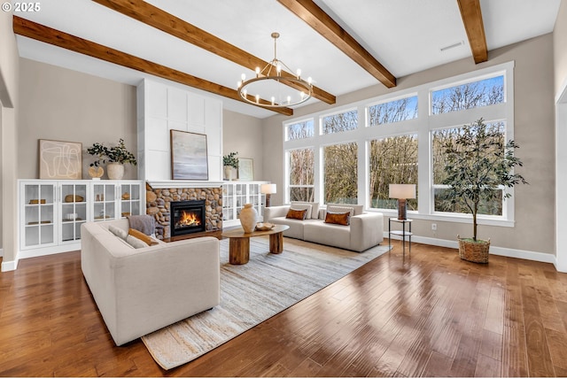 living room with a stone fireplace, wood finished floors, visible vents, baseboards, and an inviting chandelier