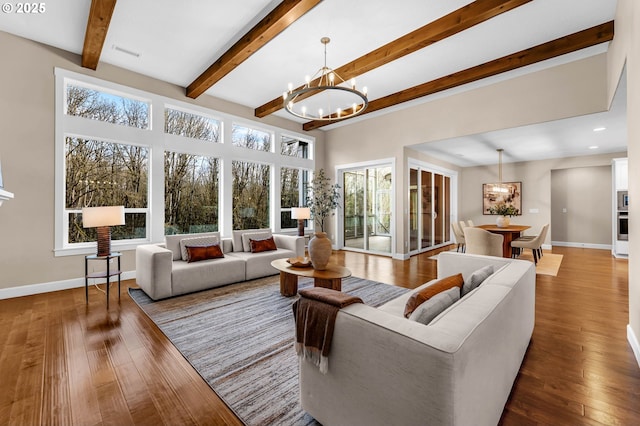 living area with wood-type flooring, visible vents, baseboards, and a notable chandelier