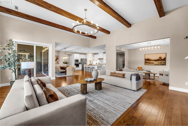 living room with wood-type flooring, visible vents, a chandelier, beamed ceiling, and baseboards