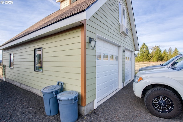 view of home's exterior with an attached garage and a shingled roof