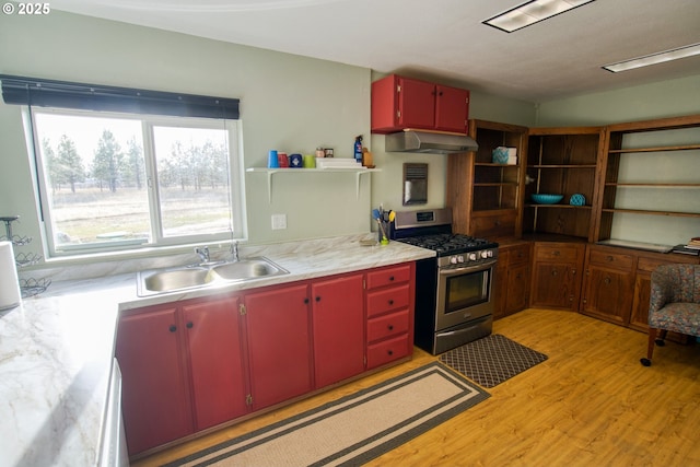 kitchen featuring red cabinetry, open shelves, a sink, gas range, and under cabinet range hood