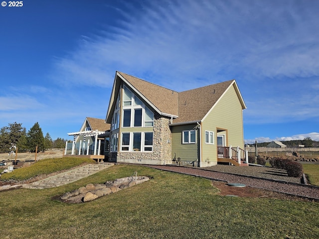 back of house featuring a yard and a shingled roof