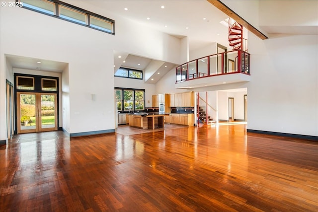 unfurnished living room with wood-type flooring, french doors, and a high ceiling