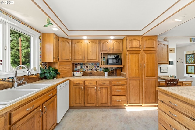 90726 Sanddollar Ln, Coos Bay, OR 97420 - kitchen with white dishwasher, a sink, black microwave, decorative backsplash, and brown cabinetry