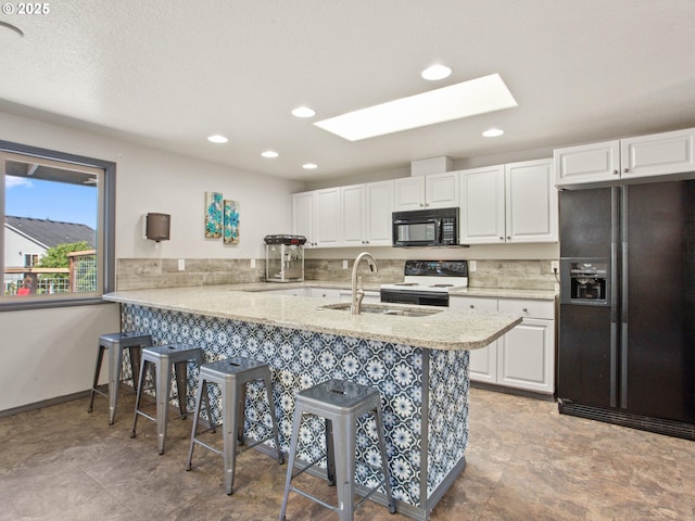 5417 N St, Washougal, WA 98671 - kitchen featuring black appliances, a sink, a breakfast bar, a skylight, and white cabinetry