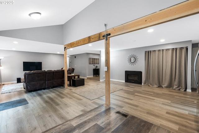 living room with visible vents, a fireplace, baseboards, and wood finished floors