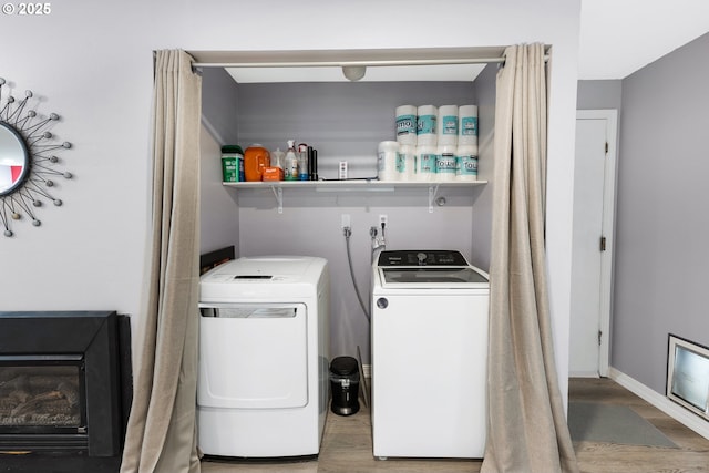 washroom featuring laundry area, independent washer and dryer, baseboards, and wood finished floors