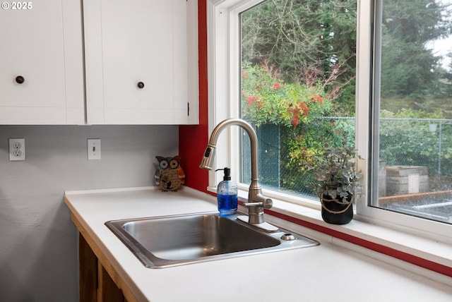 kitchen with a sink, white cabinets, and light countertops