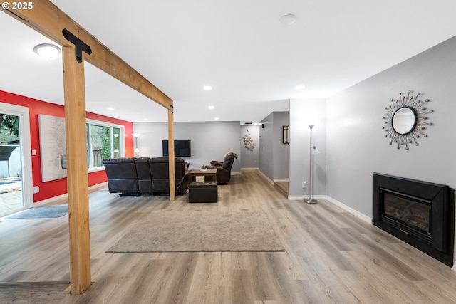 living area with a glass covered fireplace, baseboards, recessed lighting, and light wood finished floors