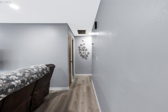 hall featuring baseboards, visible vents, and wood finished floors