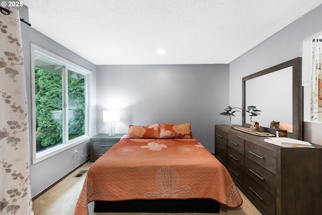 bedroom with visible vents, light colored carpet, and a textured ceiling