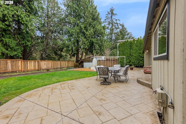 view of patio / terrace with outdoor dining area, a fenced backyard, a storage shed, and an outdoor structure