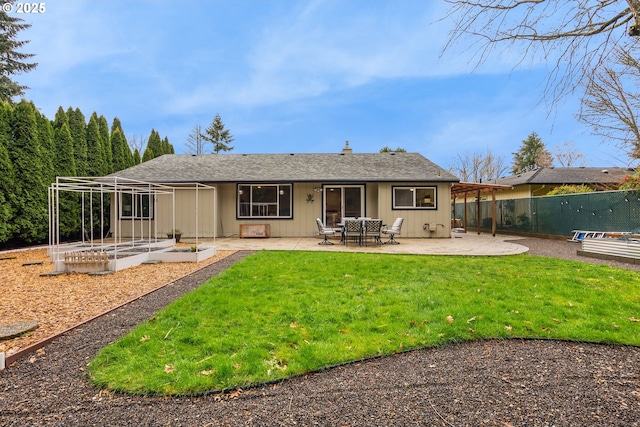 back of property with fence, a garden, a shingled roof, a patio area, and a lawn