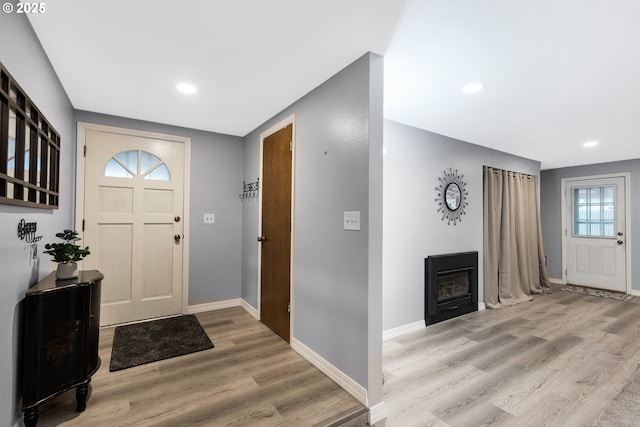 entryway with a glass covered fireplace, baseboards, recessed lighting, and light wood-type flooring