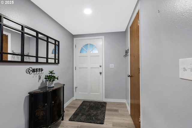 foyer with baseboards and light wood-style floors