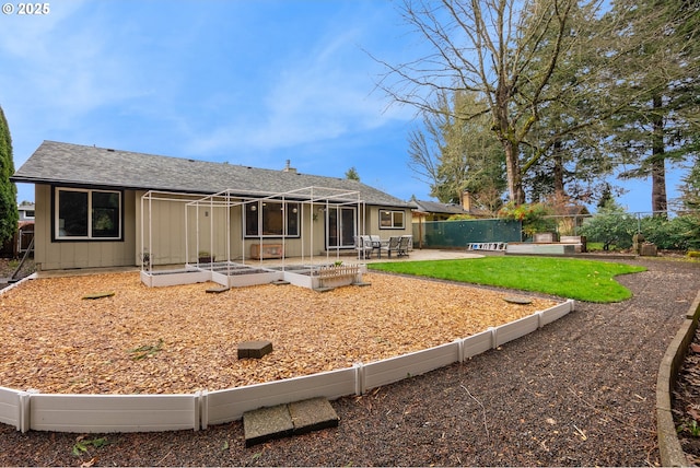 rear view of property featuring board and batten siding, a patio area, a vegetable garden, a fenced backyard, and a shingled roof