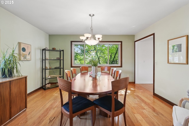 dining area with baseboards, light wood finished floors, and a notable chandelier